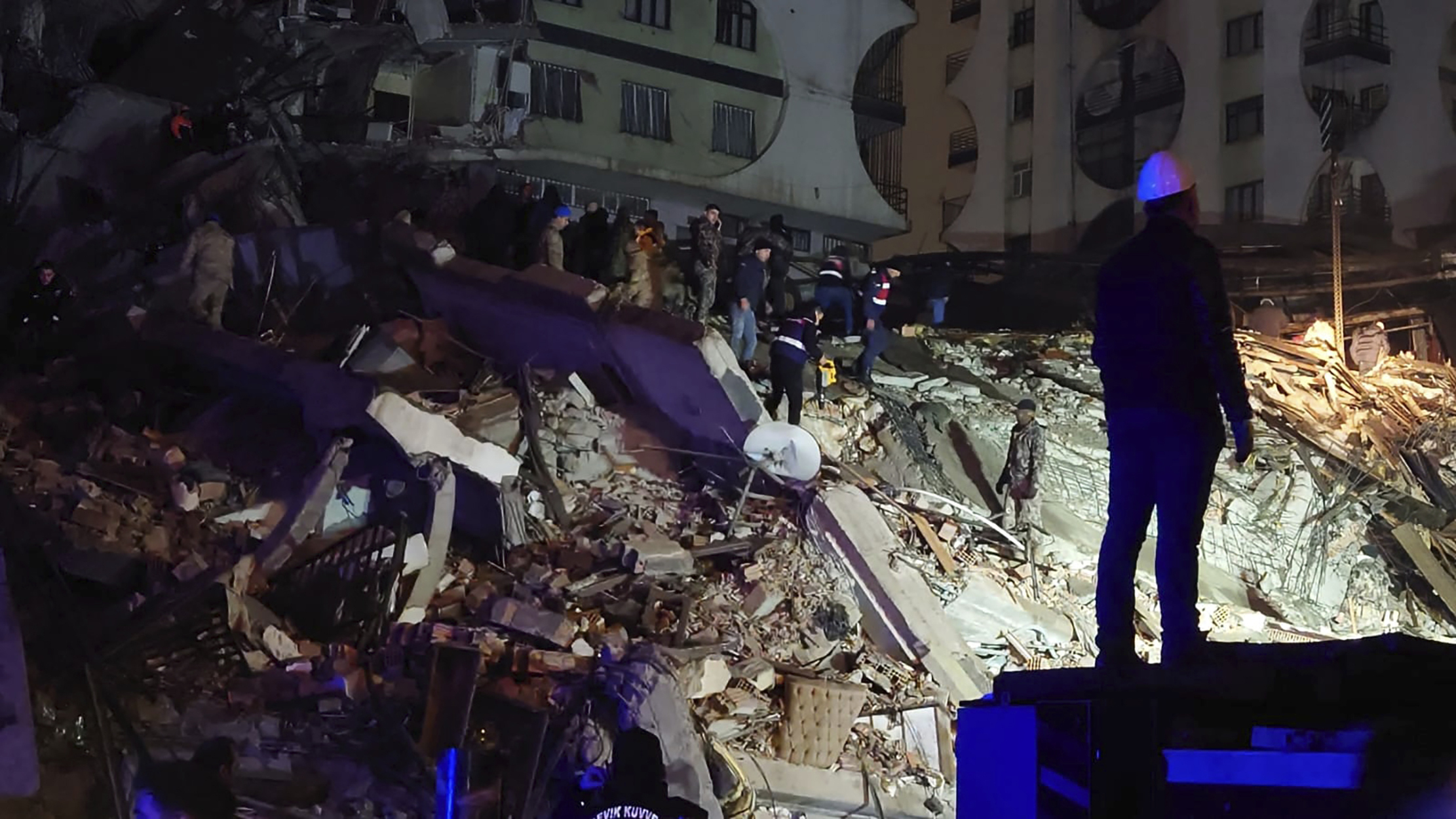 Gente trata de llegar hasta residentes atrapados en un edificio derruido en Diyarbakir, en el sureste de Turquía, el lunes 6 de febrero de 2023. Un potente terremoto causó daños significativos en el sureste de Turquía y Siria. Al menos 138 personas murieron, y se temía que la cifra siguiera subiendo. (AP Foto/Mahmut Bozarsan)