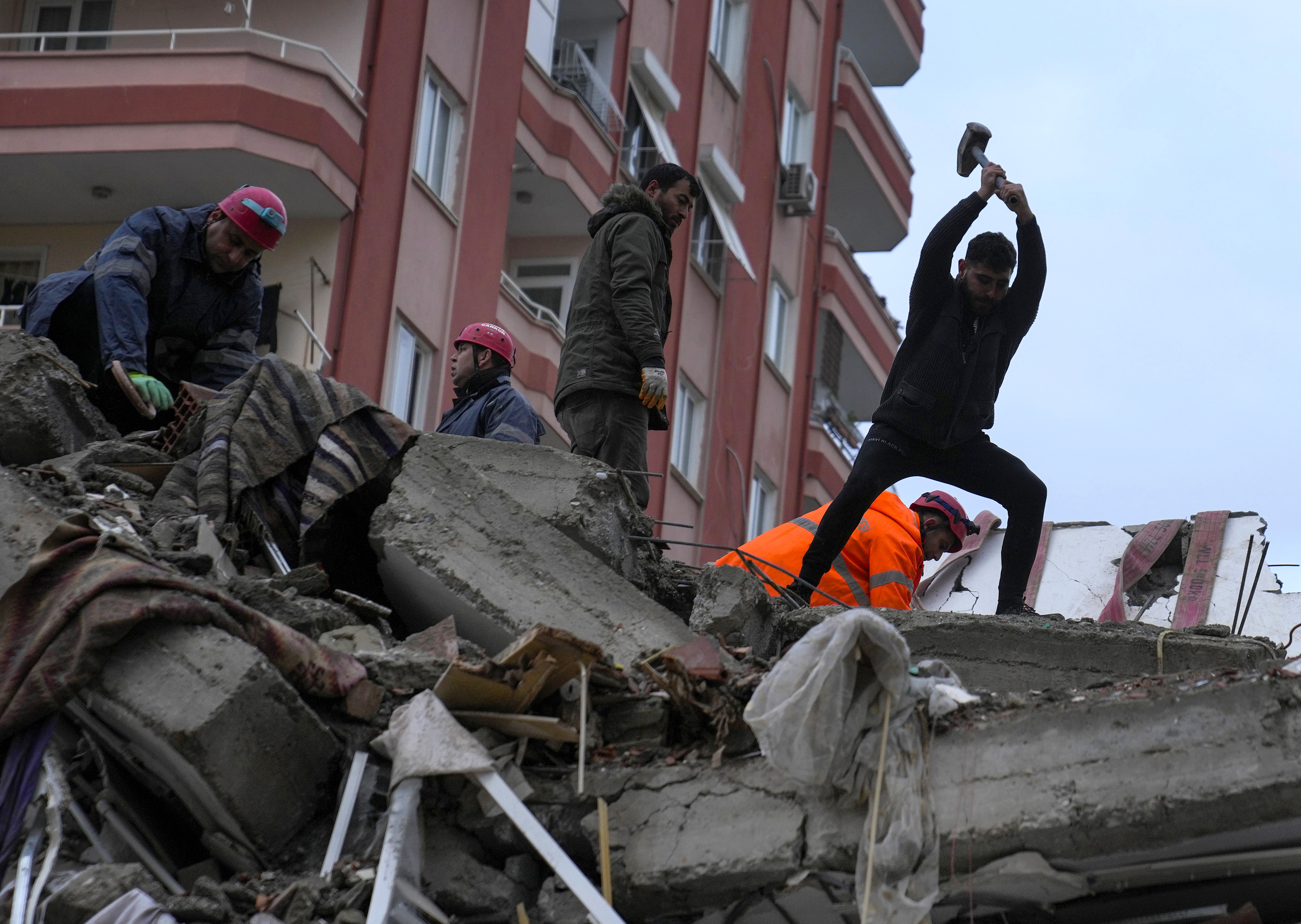 Rescatistas buscan a personas desaparecidas en un edificio que se desplomó tras un terremoto, el lunes 6 de febrero de 2023, en Adana, Turquía. (AP Foto/Khalil Hamra)