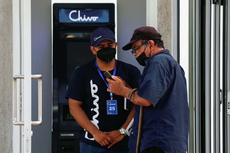 Un trabajador ayuda a un hombre con el uso de bitcoin frente a un cajero automático de "Chivo", la billetera digital respaldada por el gobierno salvadoreño, en San Salvador, El Salvador. 8 de septiembre de 2021. (REUTERS/Jose Cabezas)
