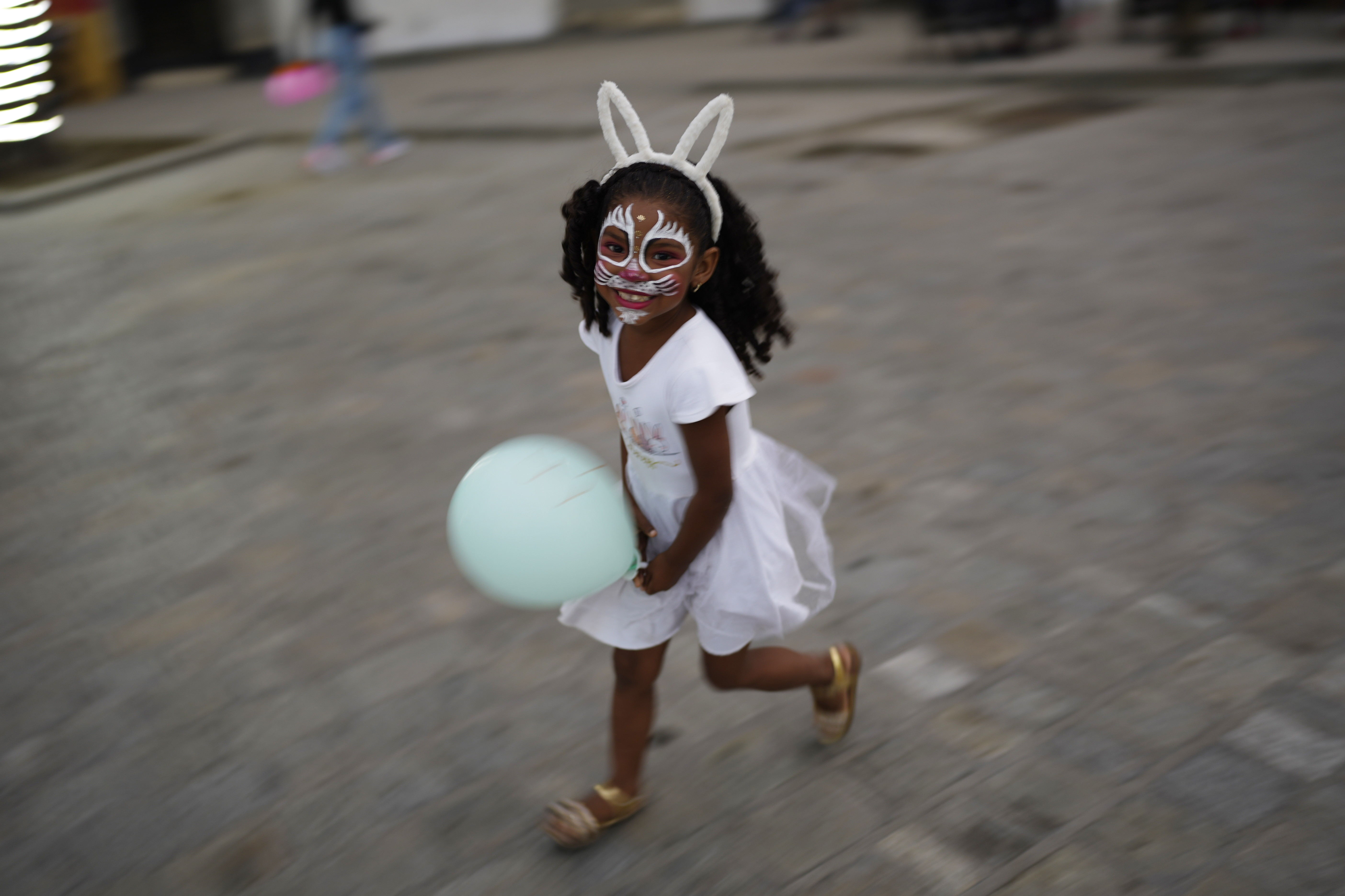 Una niña corre por una plaza con la cara pintada, en La Guaira, Venezuela, el 15 de febrero de 2023. Los venezolanos se preparan para celebrar el Carnaval. (AP Foto/Ariana Cubillos)