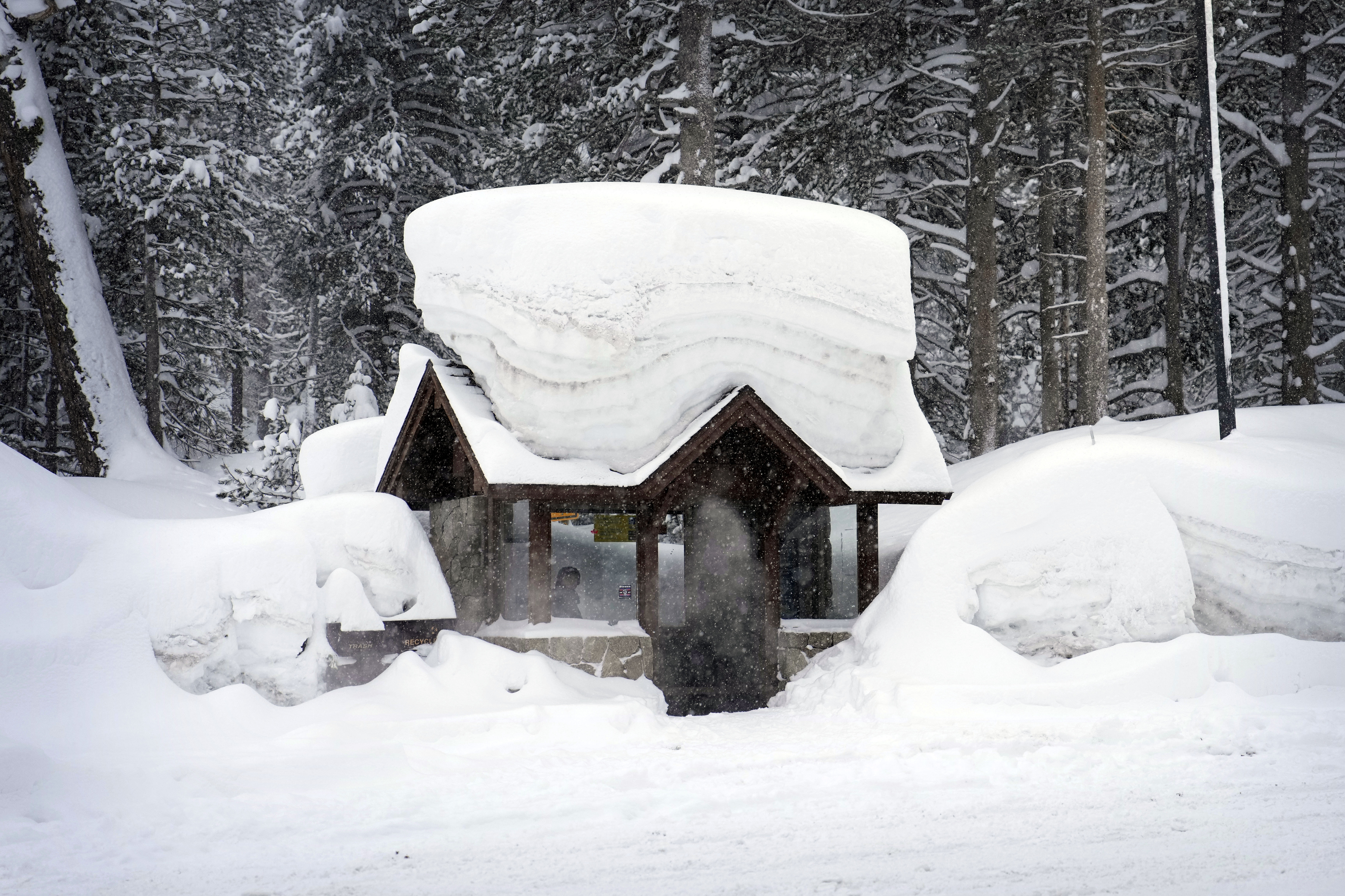 Una persona permanece en una parada de autobús cubierta por la nieve el viernes 24 de febrero de 2023, en Olympic Valley, California. (AP Foto/John Locher)