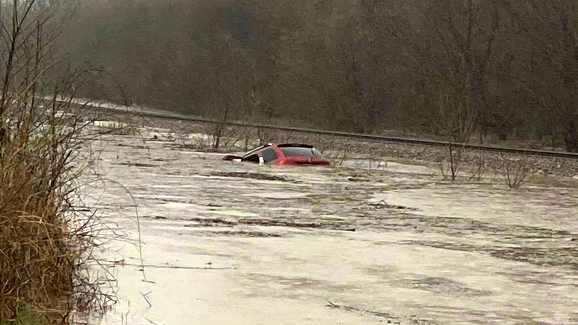 En esta foto proporcionada por Layton Hoyer, se ve un auto rojo sumergido en agua de inundación, la madrugada del viernes 24 de marzo de 2023. Hoyer rescató a una anciana del automóvil. (Layton Hoyer vía AP)