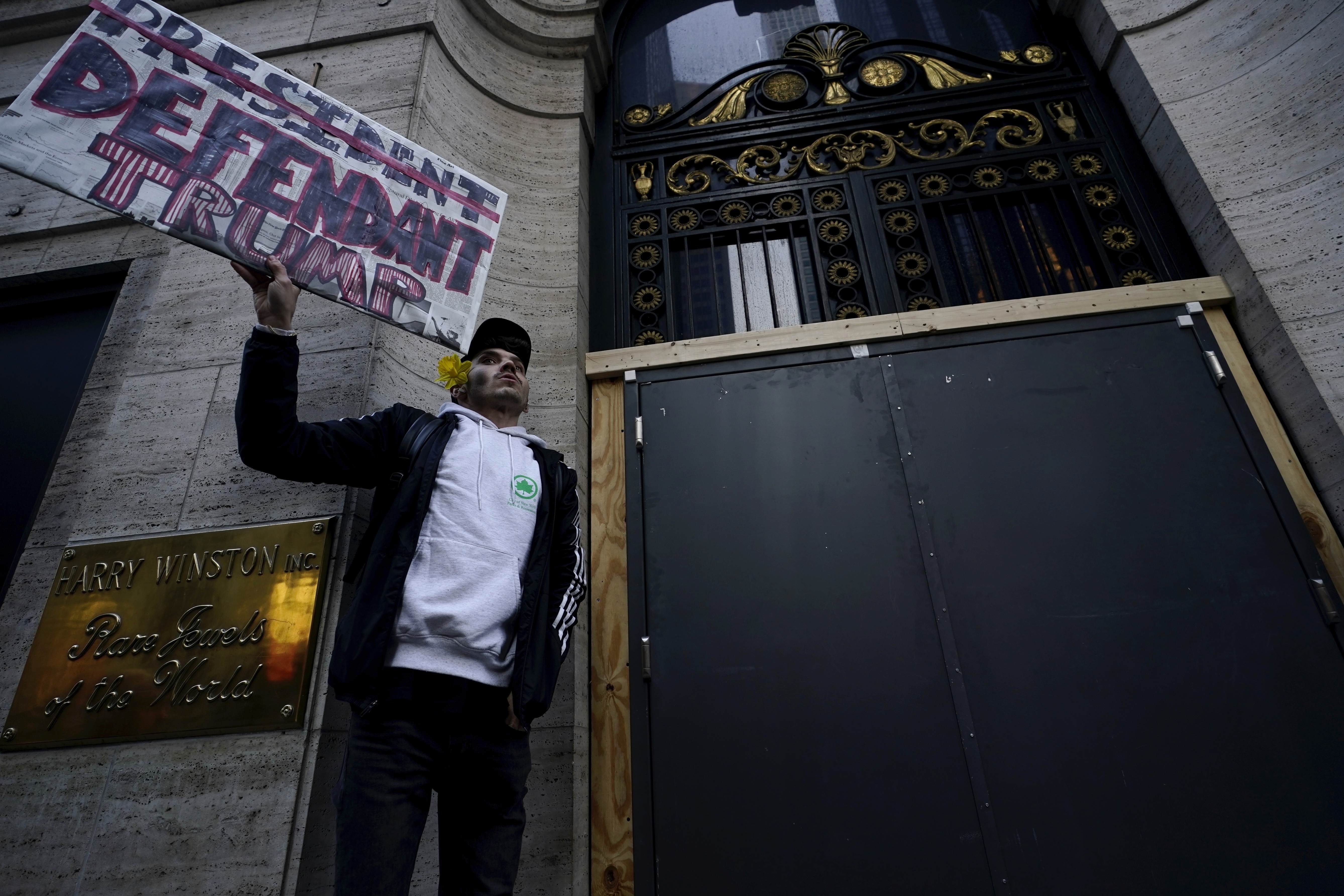 Lucas Camp, de Astoria, sostiene un cartel junto a la Trump Tower el martes 4 de abril de 2023 en Nueva York. El expresidente Donald Trump sería procesado el martes para enfrentar cargos penales derivados de pagos para silenciar a mujeres durante su campaña en 2016. (AP Foto/Bryan Woolston)