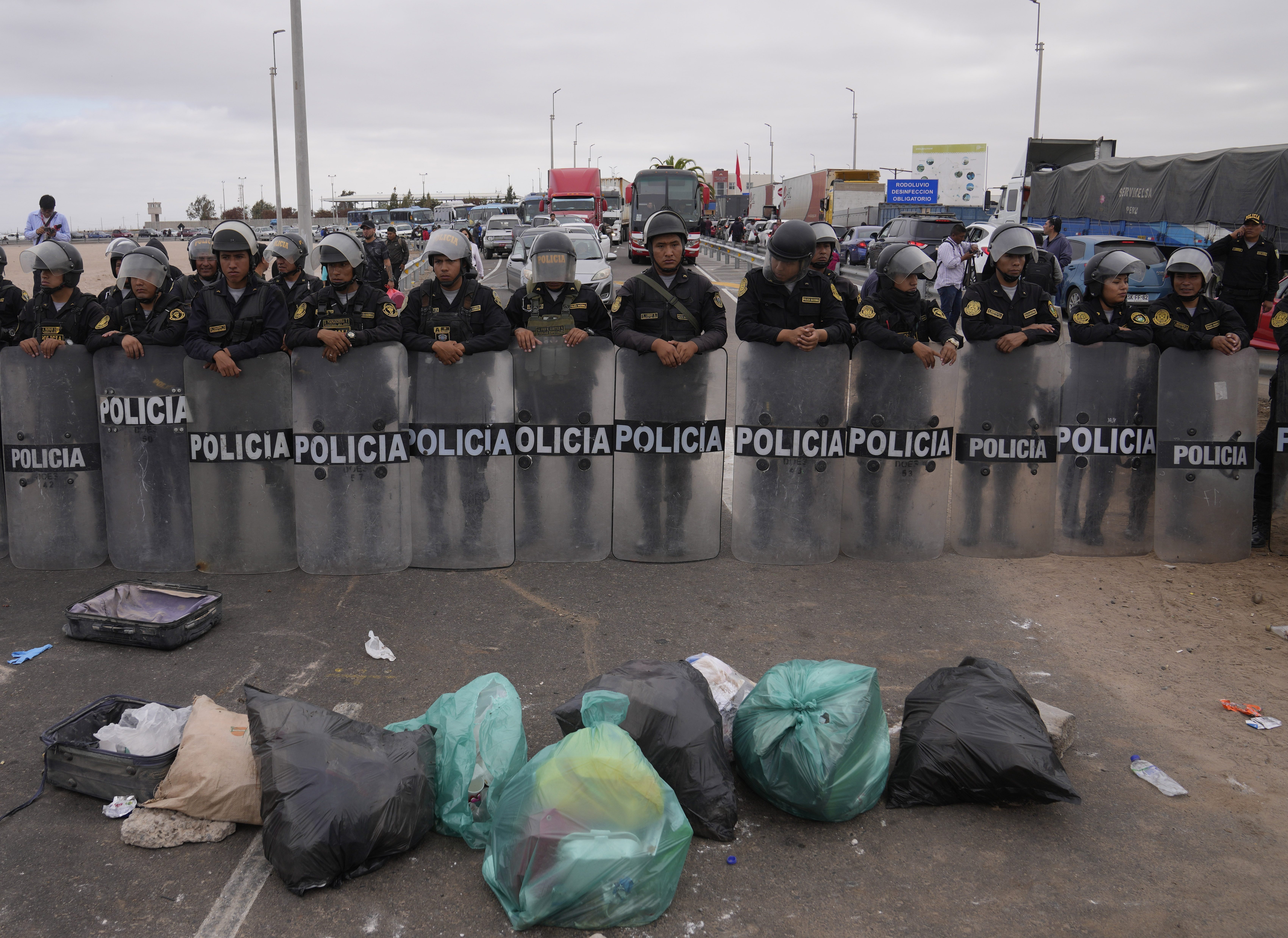 Migrantes venezolanos bloquean la entrada a Chile con basura frente a una barricada de la policía antidisturbios peruana en la frontera peruana con Chile, en Tacna, Perú, el sábado 29 de abril de 2023. Una crisis migratoria en la frontera entre Chile y Perú se intensificó a medida que cientos de migrantes quedaron varados sin poder cruzar a Perú. (Foto AP/Martín Mejía)