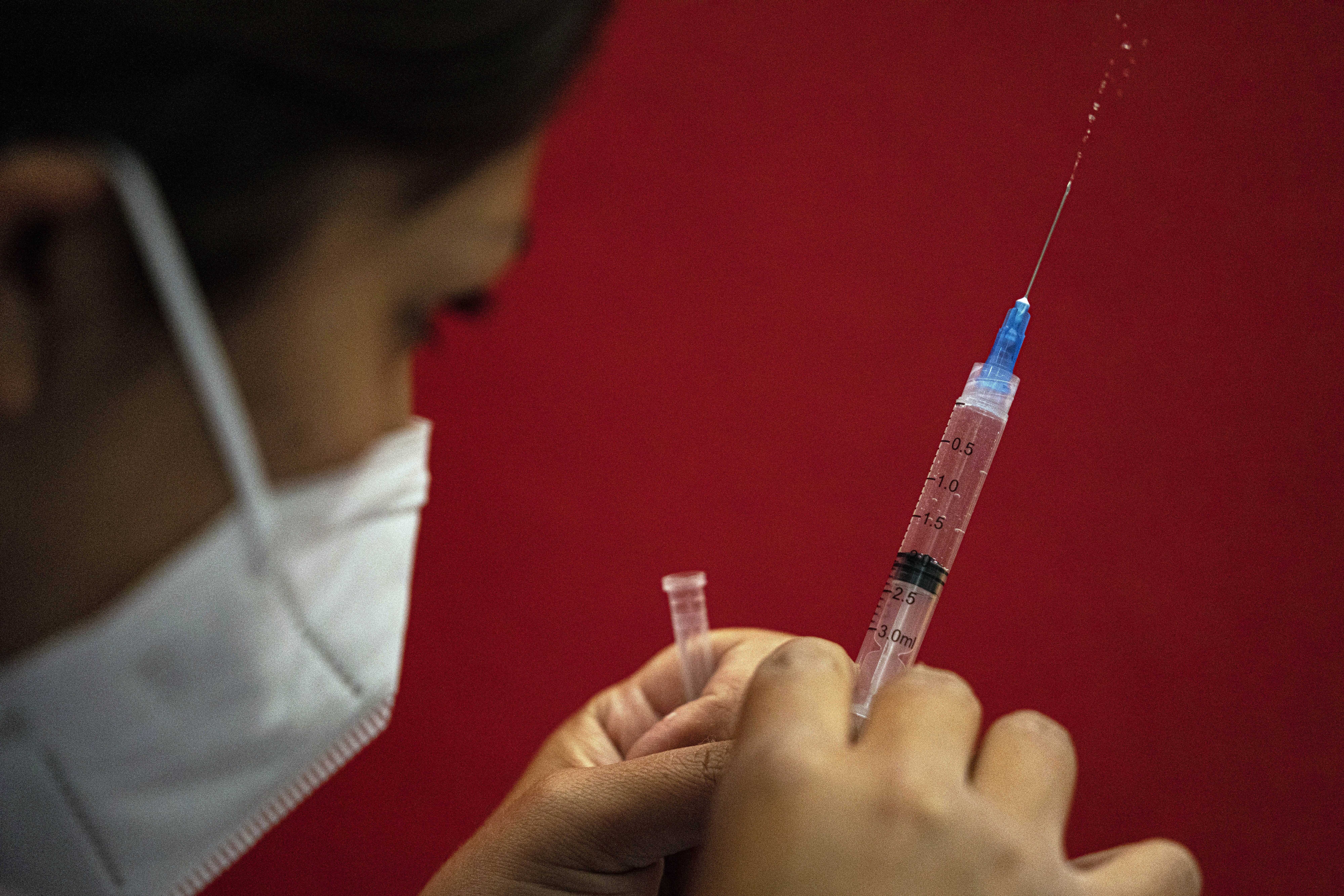 ARCHIVO - Una trabajadora de la salud prepara una dosis de la vacuna de Pfizer para el COVID-19 al inicio de una segunda campaña de vacunación de refuerzo contra el nuevo coronavirus para personas mayores de 55 años en una instalación deportiva en Santiago, Chile, el 7 de febrero de 2022. Chile, el primer país de la región en iniciar la inmunización con la vacuna bivalente contra el coronavirus original y la variante omicron, está lejos de la meta de vacunar a los mayores de 50 años y a los enfermos crónicos. (AP Photo/Esteban Felix, Archivo)