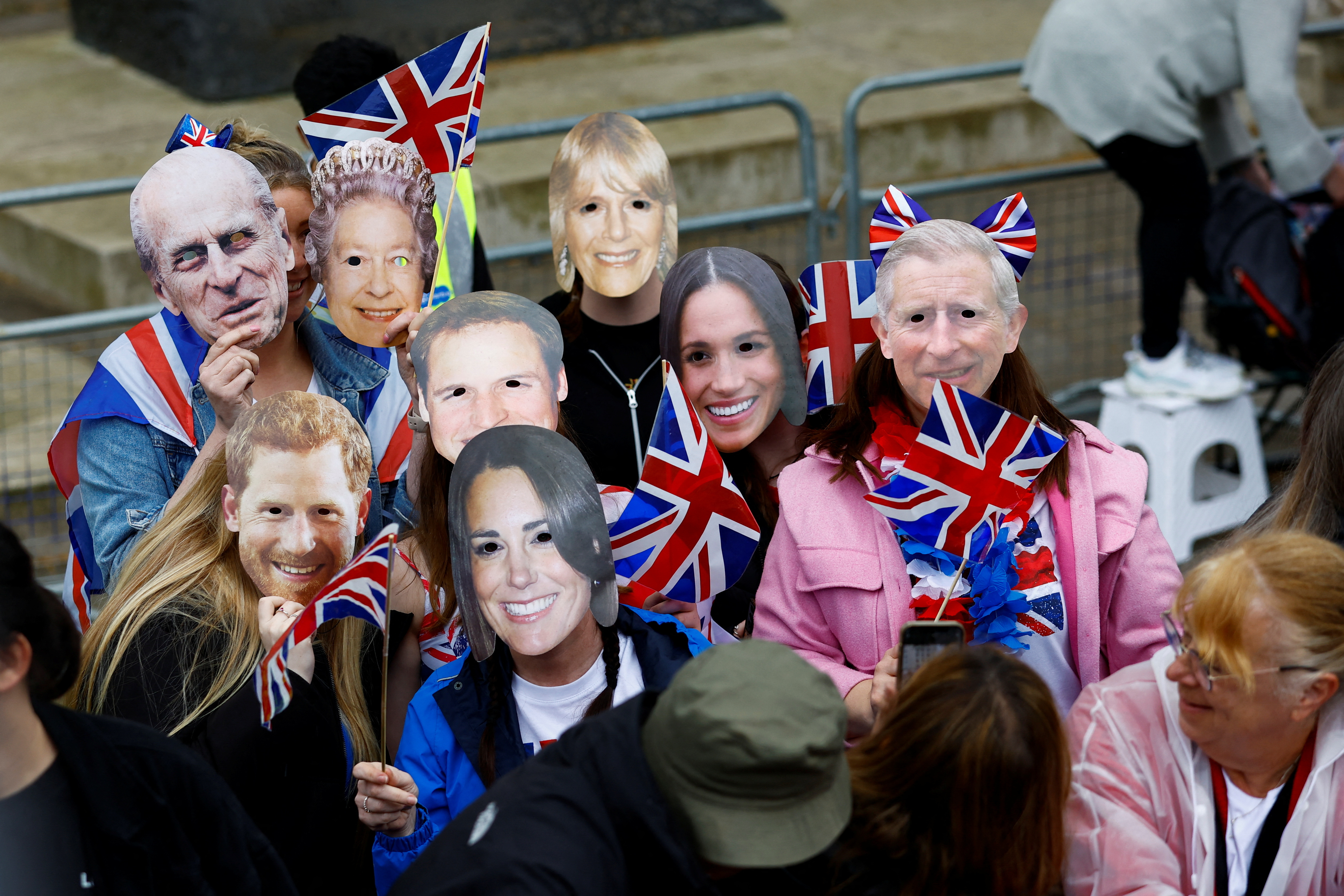 Personas con máscaras que representan a miembros de la familia real británica esperan para ver la procesión del rey Carlos y la reina Camilla de Gran Bretaña a su ceremonia de coronación del Palacio de Buckingham a la Abadía de Westminster, en Whitehall, en Londres, Gran Bretaña 6 de mayo 2023. REUTERS/Andrew Boyers