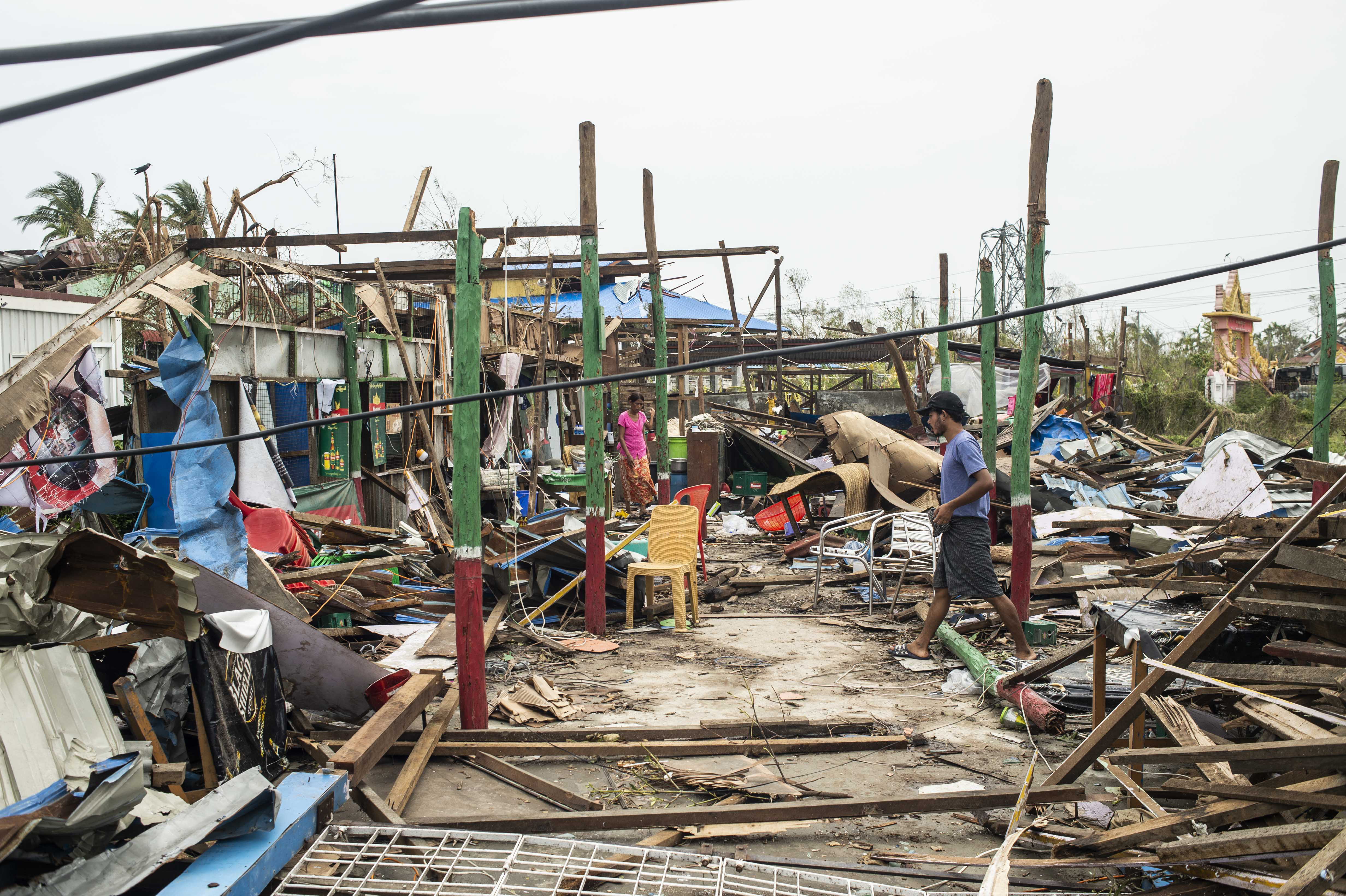 Residentes locales caminan frente a edificios dañados tras el paso del ciclón Mocha, el martes 16 de mayo de 2023, en el municipio de Sittwe, en el estado de Rakhine, Myanmar. (AP Foto)