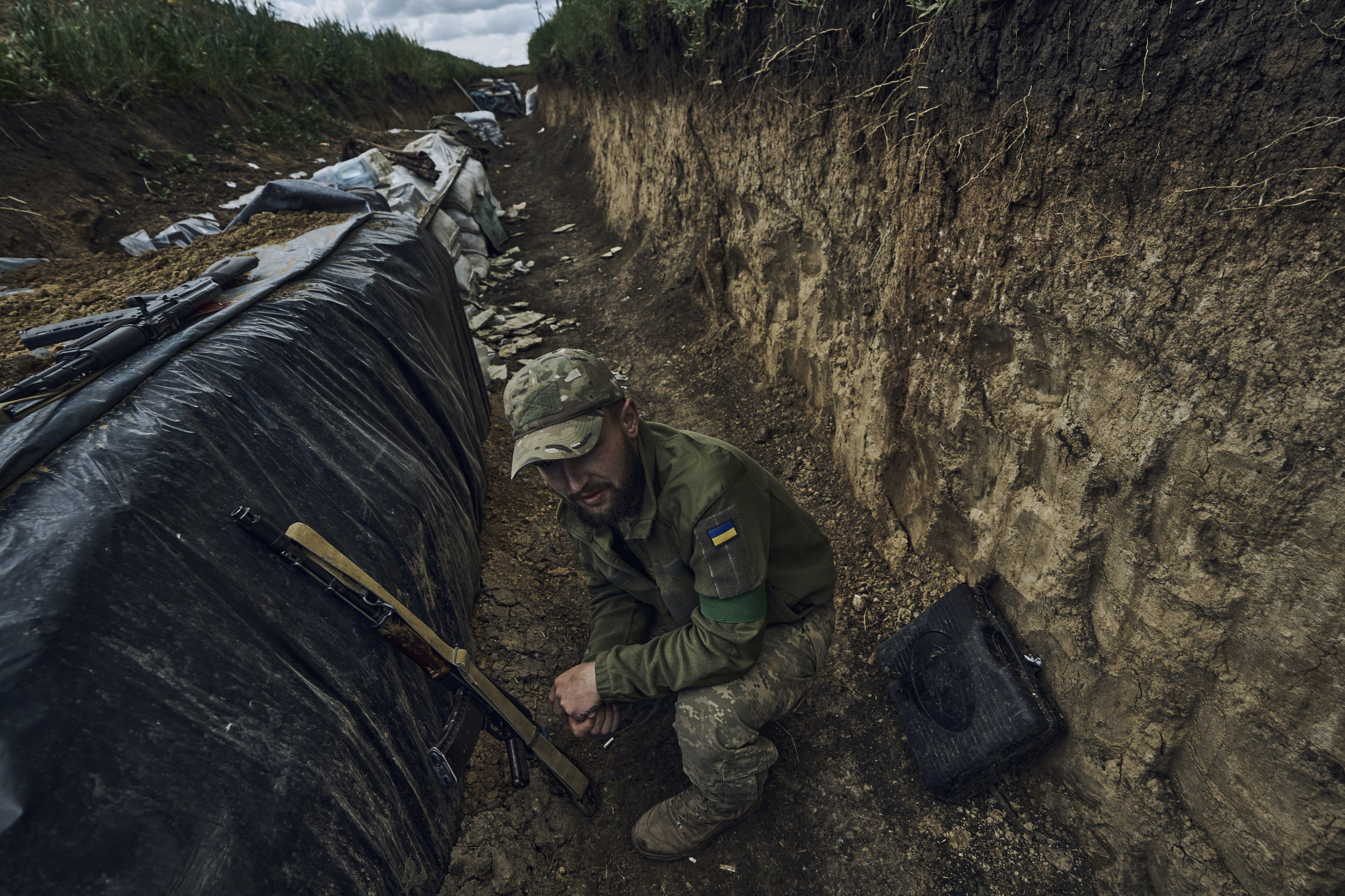 Un soldado ucraniano se sienta en una trinchera en el frente cerca de Bájmut, en la región de Donetsk, Ucrania, el lunes 22 de mayo de 2023. (AP Foto/Libkos)